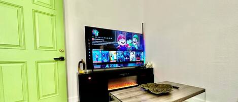 Una sala moderna con un televisor de pantalla plana montado en un mueble negro, una mesa de centro de vidrio y una puerta verde.