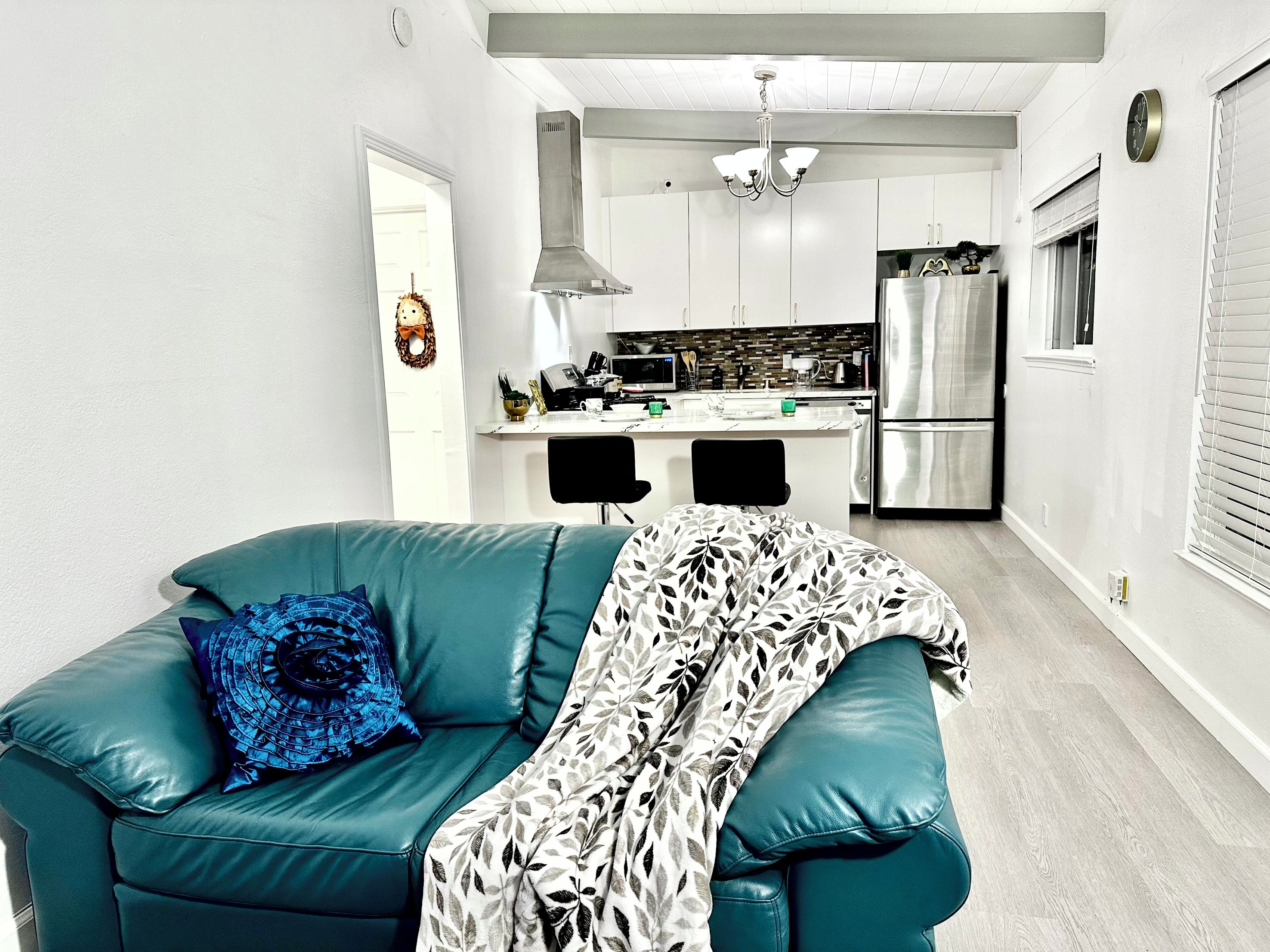 A modern kitchen with white cabinets, a stainless steel refrigerator, and a black chair.
