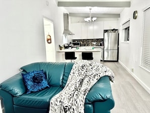 A modern kitchen with white cabinets, a stainless steel refrigerator, and a black chair.