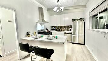 A modern kitchen with a central island, stainless steel appliances, and a chandelier.