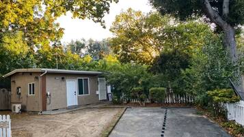 A single-story building with a garage, surrounded by trees and a white picket fence.