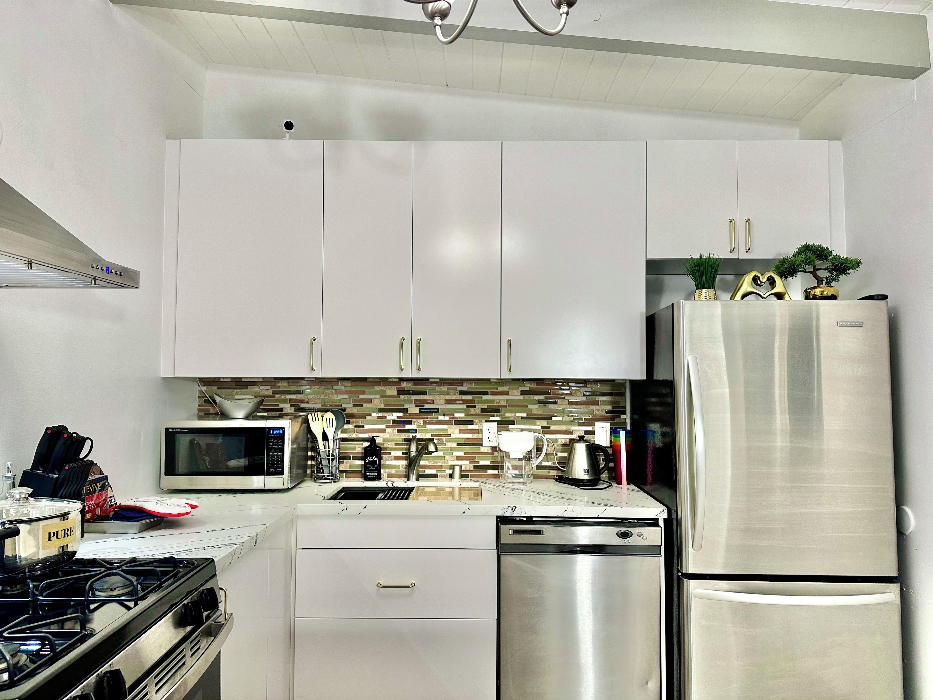 A modern kitchen with white cabinets, stainless steel appliances, and a tiled backsplash.