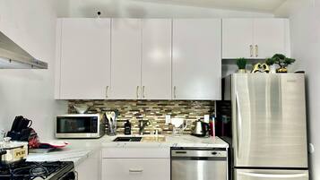 A modern kitchen with white cabinets, stainless steel appliances, and a tiled backsplash.