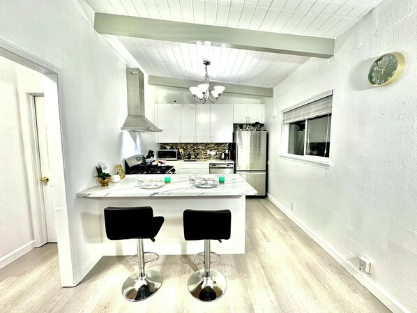 A modern kitchen with a central island, stainless steel appliances, and a ceiling light fixture.