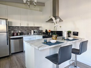 Cozinha moderna com ilha central, eletrodomésticos de aço inoxidável e banquetas.