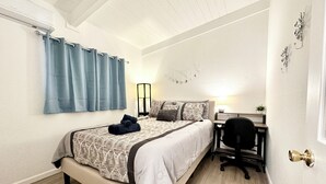 A bedroom with a bed, a desk, and a chair.
