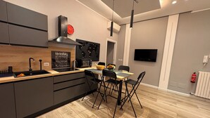 Une cuisine moderne dotée d’un îlot central, de meubles de rangement noirs et d’un coin repas avec une table et des chaises.