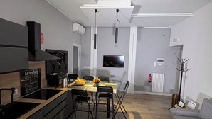 Une cuisine moderne avec un coin repas, un plancher en bois et un canapé gris.