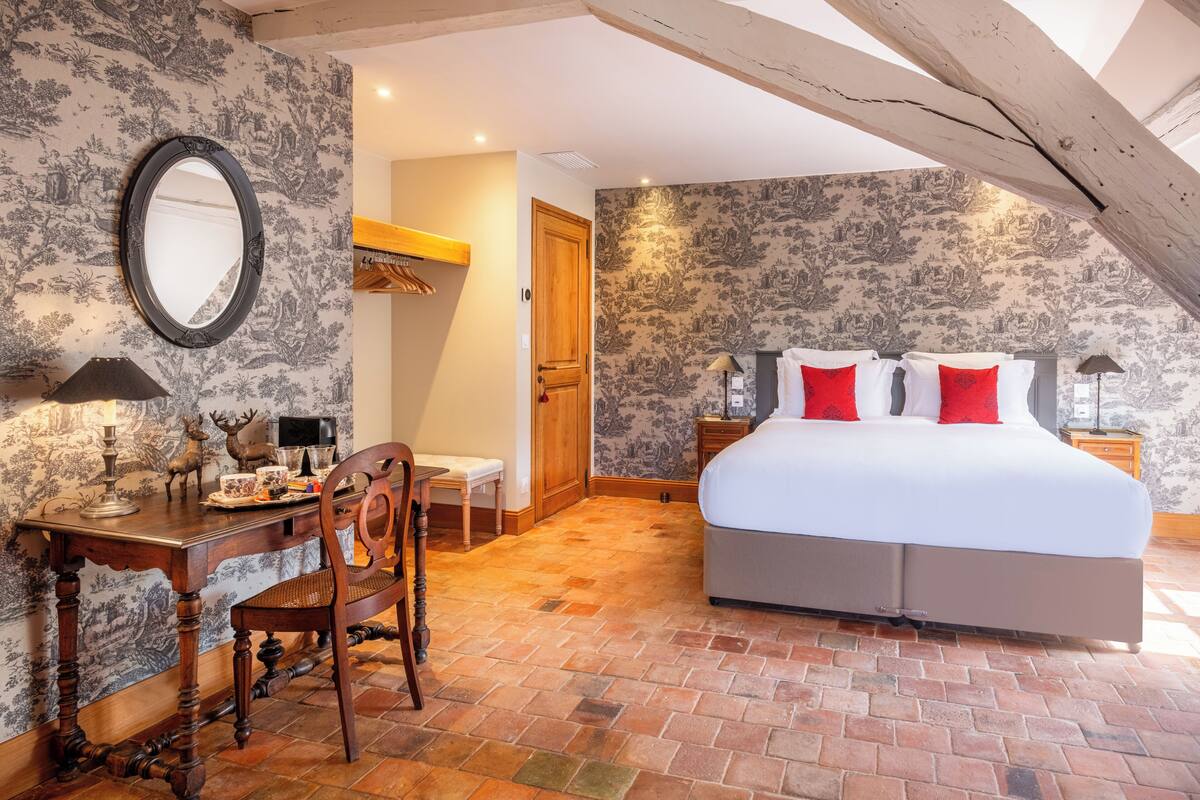 Een slaapkamer met een groot bed, een houten bureau, een stoel en een spiegel.