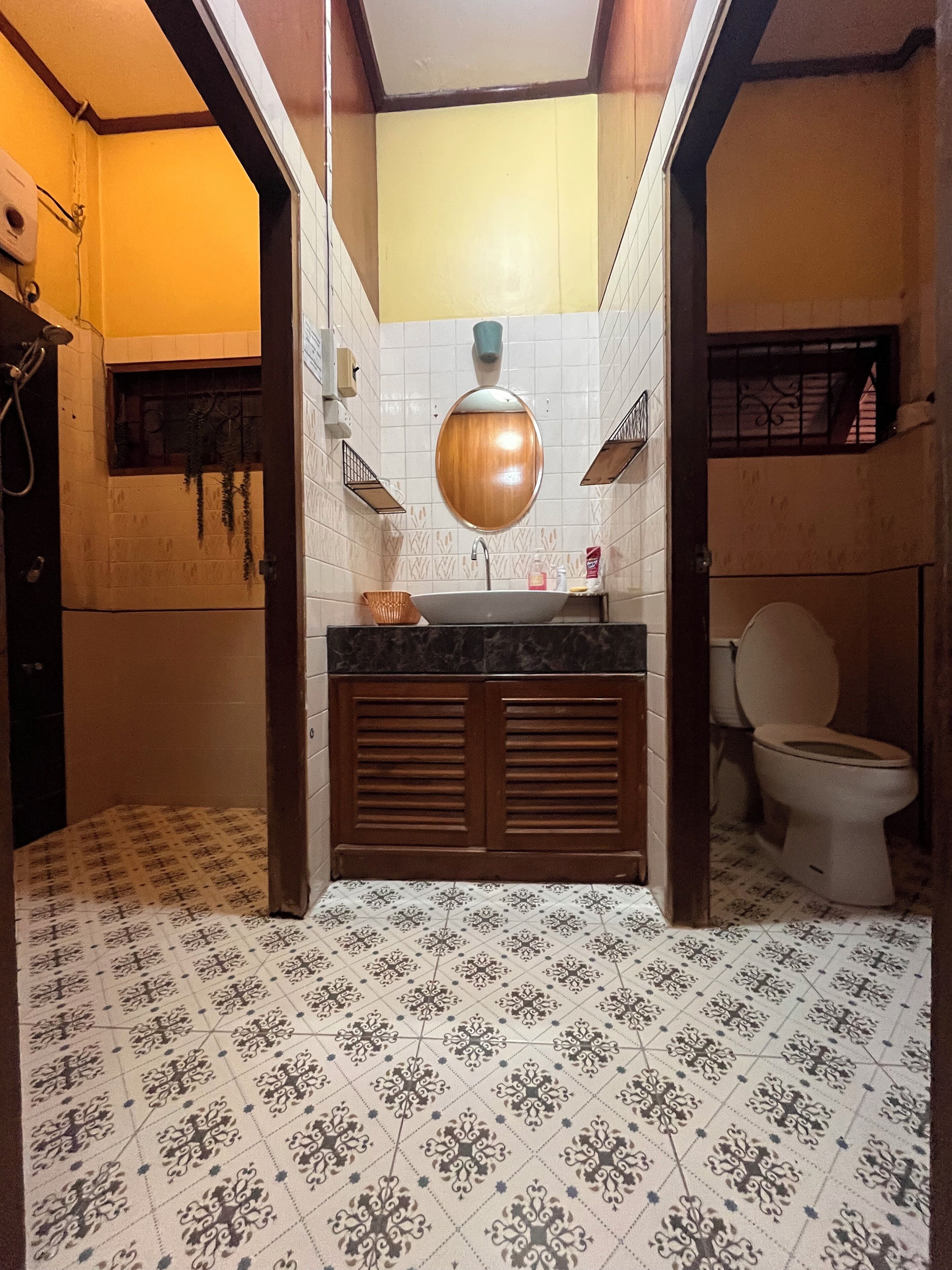 A bathroom with a tiled floor, a sink with a mirror above, and a toilet.