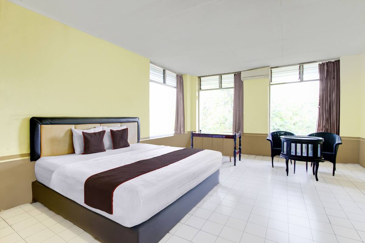 Une chambre d’hôtel avec un grand lit, un bureau et deux chaises.