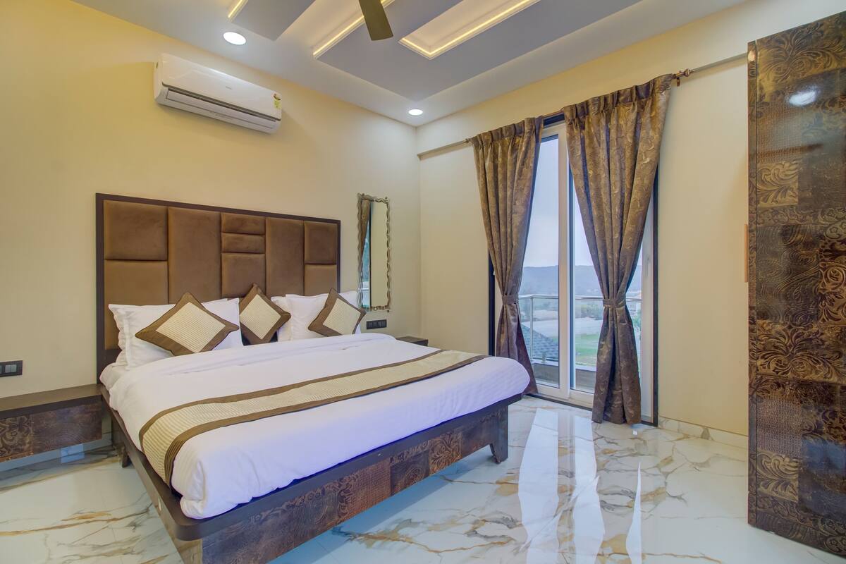 Habitación de hotel con una cama grande, ventilador de techo, aire acondicionado y vistas por la ventana.