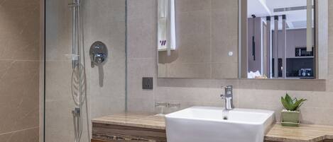 A modern bathroom with a glass-enclosed shower, a white sink, and a wooden vanity with built-in storage.