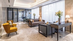 A modern hotel lobby with a seating area, a coffee table, and a vase with flowers. - W Residence Living (Dhaka)