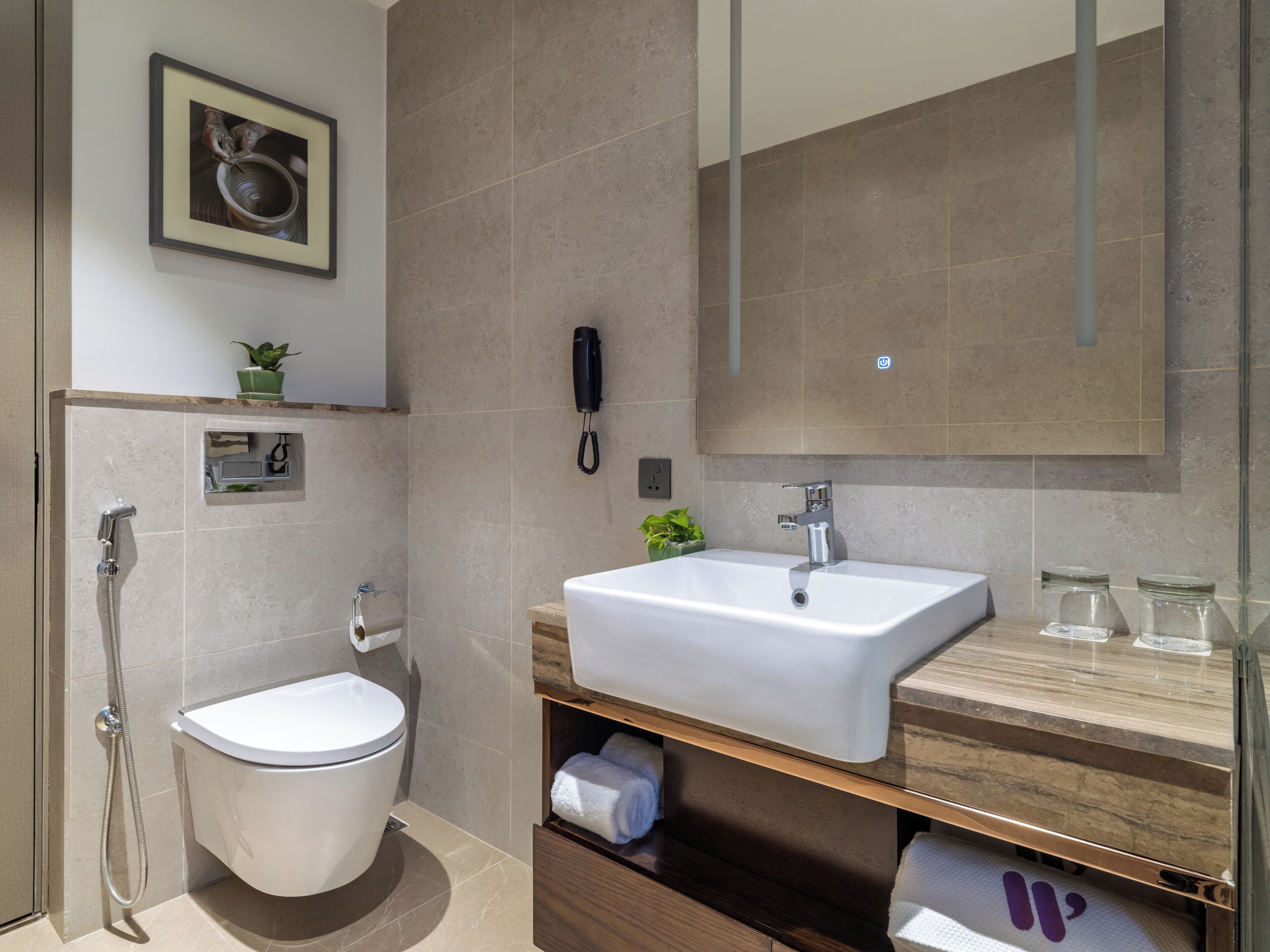 Ein modernes Badezimmer mit Toilette, Bidet und einem großen Spiegel über dem Waschbecken.