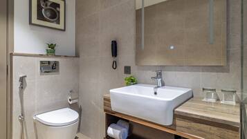 Ein modernes Badezimmer mit Toilette, Bidet und einem großen Spiegel über dem Waschbecken.
