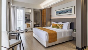A modern hotel room with a large bed, a desk, and a dining area. - W Residence Living (Dhaka)