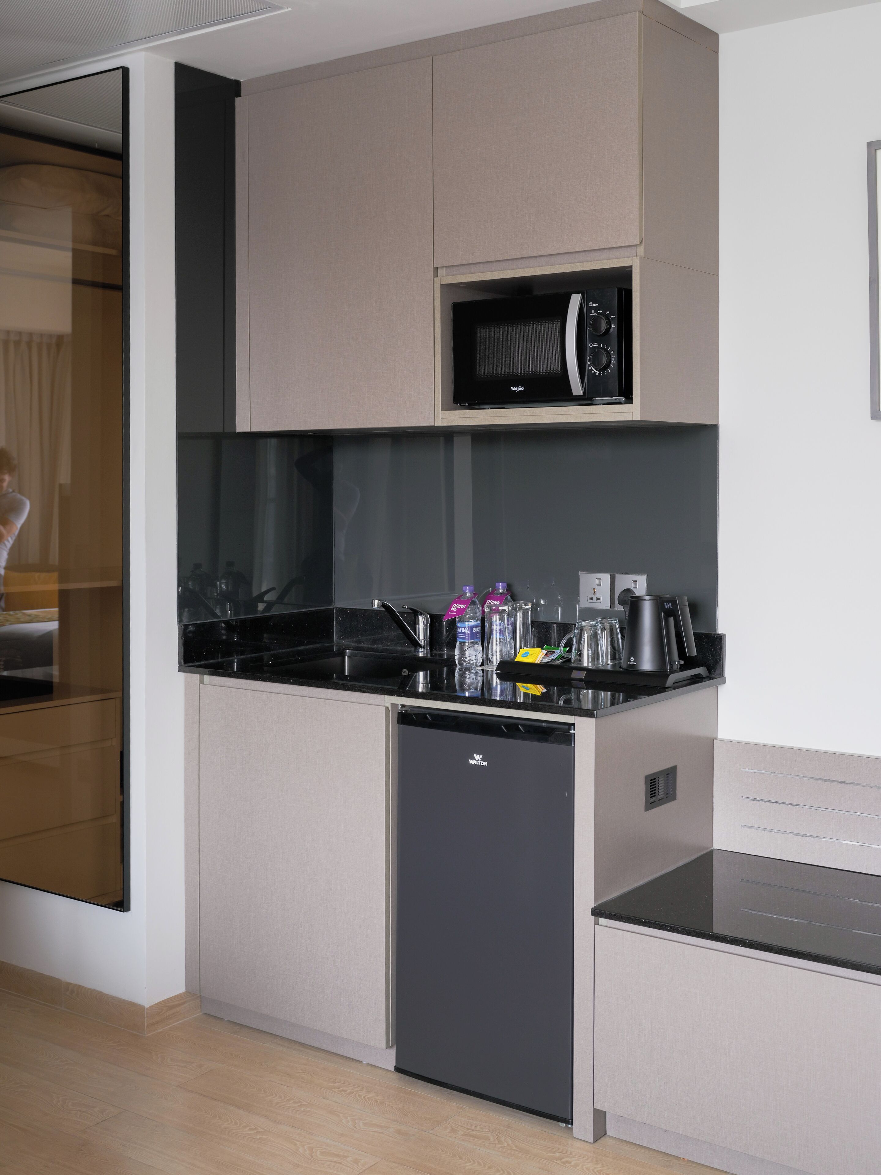 A compact kitchen with a microwave, a dishwasher, and a countertop with various items.