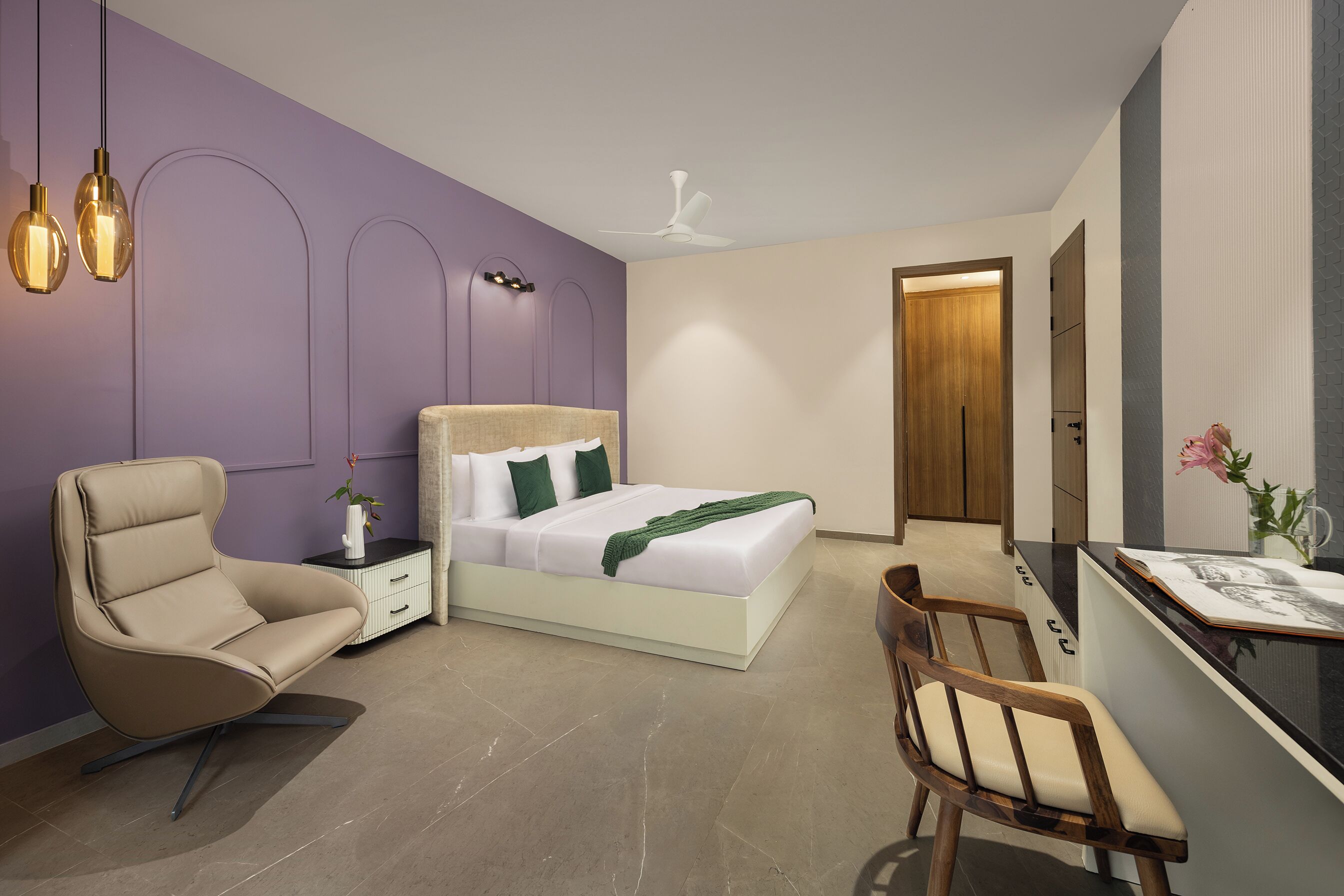 Ein modernes Schlafzimmer mit einem Bett, einem Sessel, einem Schreibtisch und einem Deckenventilator.