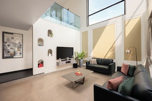 Uma sala de estar moderna com televisão de tela plana, um sofá, uma mesa de centro e um vaso com planta.