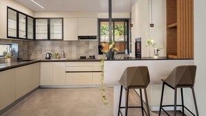 Cocina moderna con una isla central, taburetes de bar y una planta colgante.