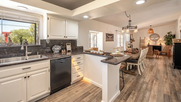 A modern kitchen with white cabinets, a built-in dishwasher, and a large island with seating. - Family Retreat 3BR InGround Pool + Spa+ Private fenced back yard+Sun Room. (Yucca Valley)