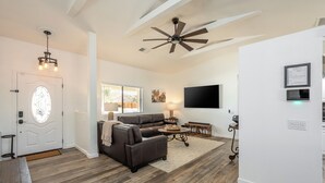 A spacious living room with a brown leather sofa, a round coffee table, and a ceiling fan. - Family Retreat 3BR InGround Pool + Spa+ Private fenced back yard+Sun Room. (Yucca Valley)