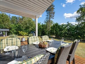 An outdoor dining area with wicker chairs and a table set for a meal.