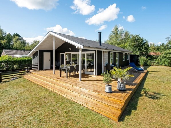 A modern house with a wooden deck, a covered patio, and a slide.