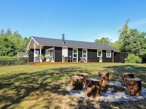 A modern house with a covered porch and a stone fire pit.