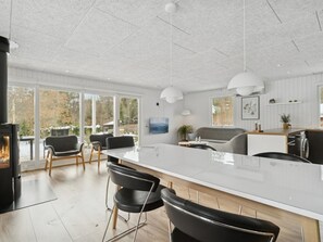 A modern kitchen with a large island, bar stools, a fireplace, and a view of the outdoors.