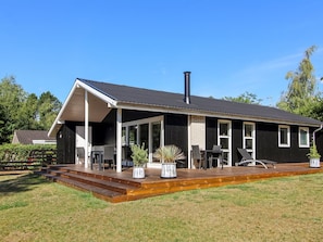 A modern house with a covered patio, a chimney, and a well-maintained lawn.
