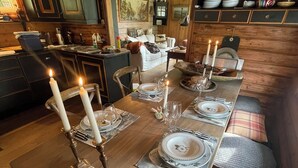 A long dining table set with candles, plates, and glasses, surrounded by wooden benches and a cozy seating area. - Winter and summer lodge for adventures, wilderness experience in the N.mountains (Innlandet)