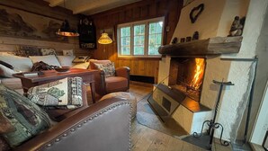 A cozy living room with a fireplace, leather armchair, and wooden flooring. - Winter and summer lodge for adventures, wilderness experience in the N.mountains (Innlandet)
