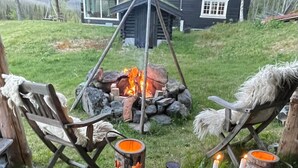 A rustic outdoor seating area with two wooden chairs, a stone table, and a fire pit. - Winter and summer lodge for adventures, wilderness experience in the N.mountains (Innlandet)