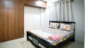 Une chambre à coucher avec un lit, une armoire en bois et un appareil de climatisation.