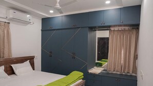 Un dormitorio con cama, armario, espejo y equipo de aire acondicionado.