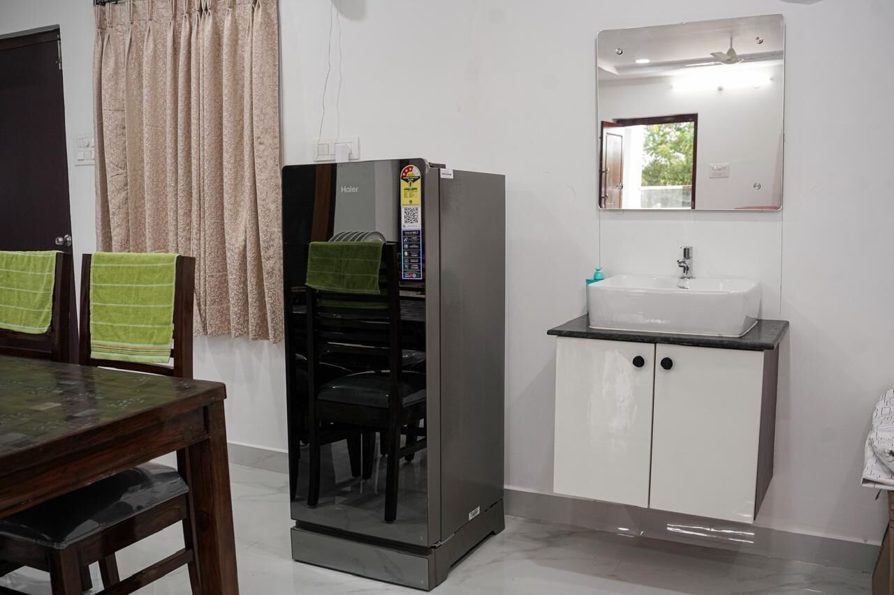 A compact living space with a dining area, a built-in refrigerator, a white sink, and a mirror above the sink.