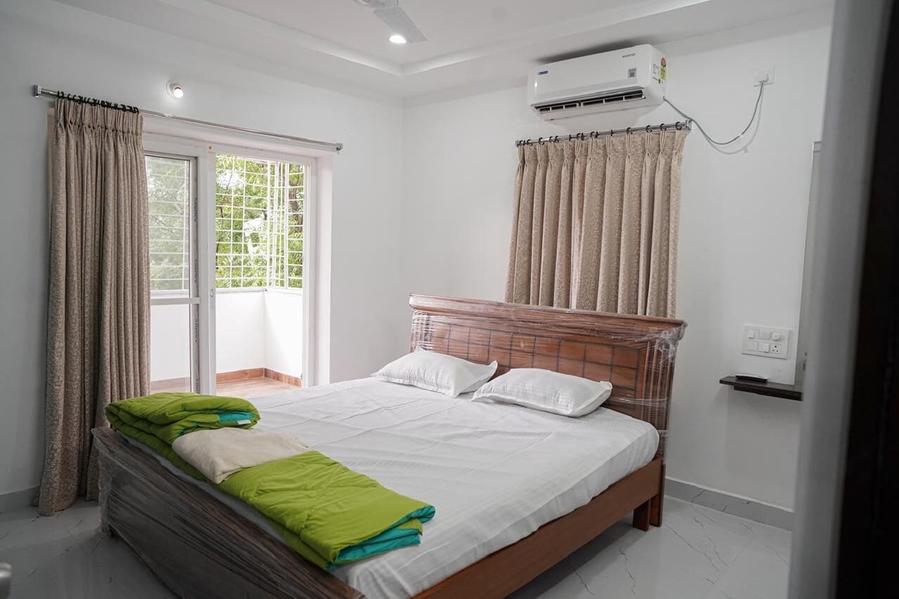 Quarto com cama, cortinas, ar condicionado e janela com vista.