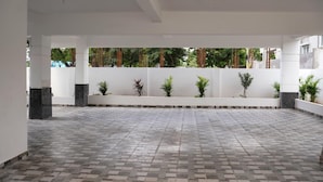 Un amplio patio interior con suelo de baldosas, paredes blancas y varias macetas con plantas.