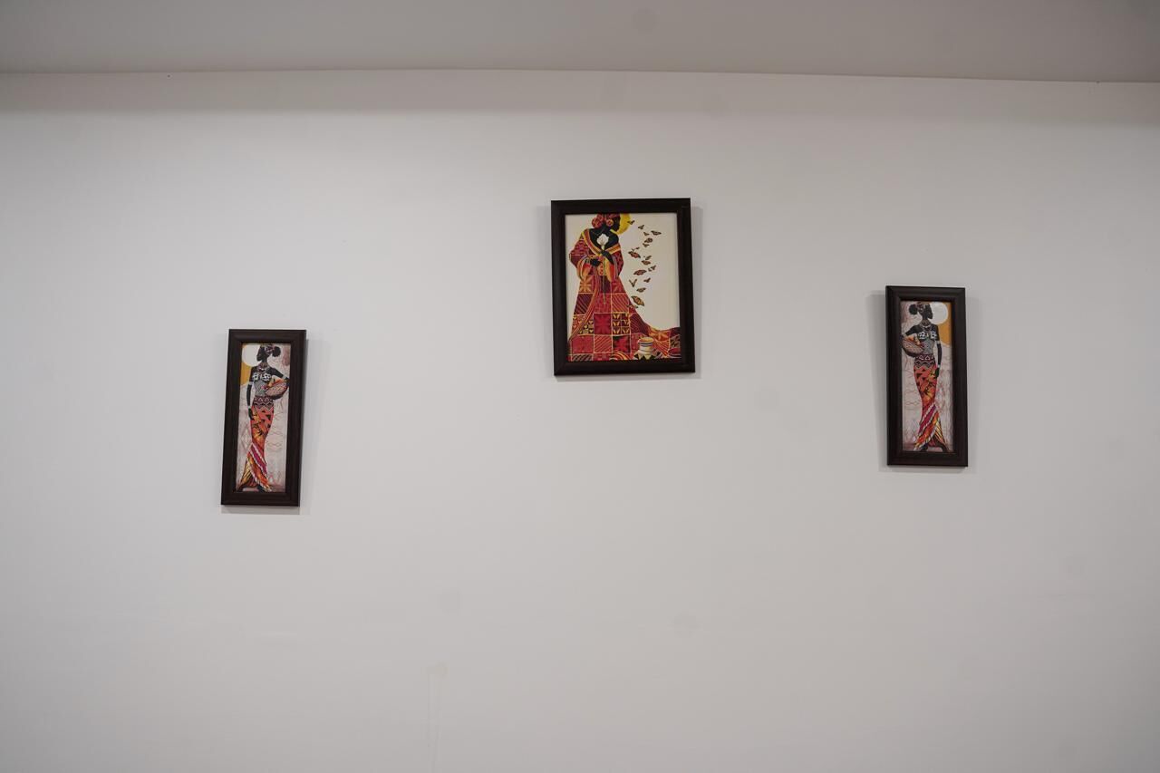 Drei gerahmte Kunstwerke an einer schlichten Wand.