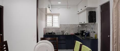 Une cuisine compacte avec un coin repas, comprenant une table avec des chaises, une fenêtre et une porte.