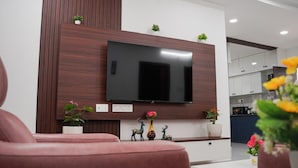 Una sala de estar moderna con un televisor de pantalla plana montado en una pared de madera, un sofá y elementos decorativos como pequeñas macetas y figuritas.