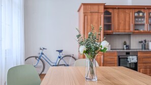 Una mesa de comedor con un florero, una silla verde y una bicicleta al fondo.