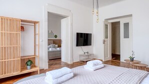 Una habitación de hotel moderna con una cama grande, un armario de madera, un televisor y una mesita con una planta.