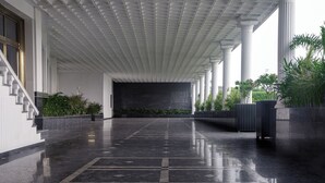 A spacious lobby with a polished marble floor, a staircase on the left, and a row of columns on the right. - TreeHouse Velis Sonipat (Ganaur)