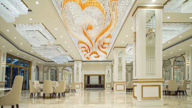 A spacious lobby with a large, ornate chandelier and a polished marble floor. - TreeHouse Velis Sonipat (Ganaur)