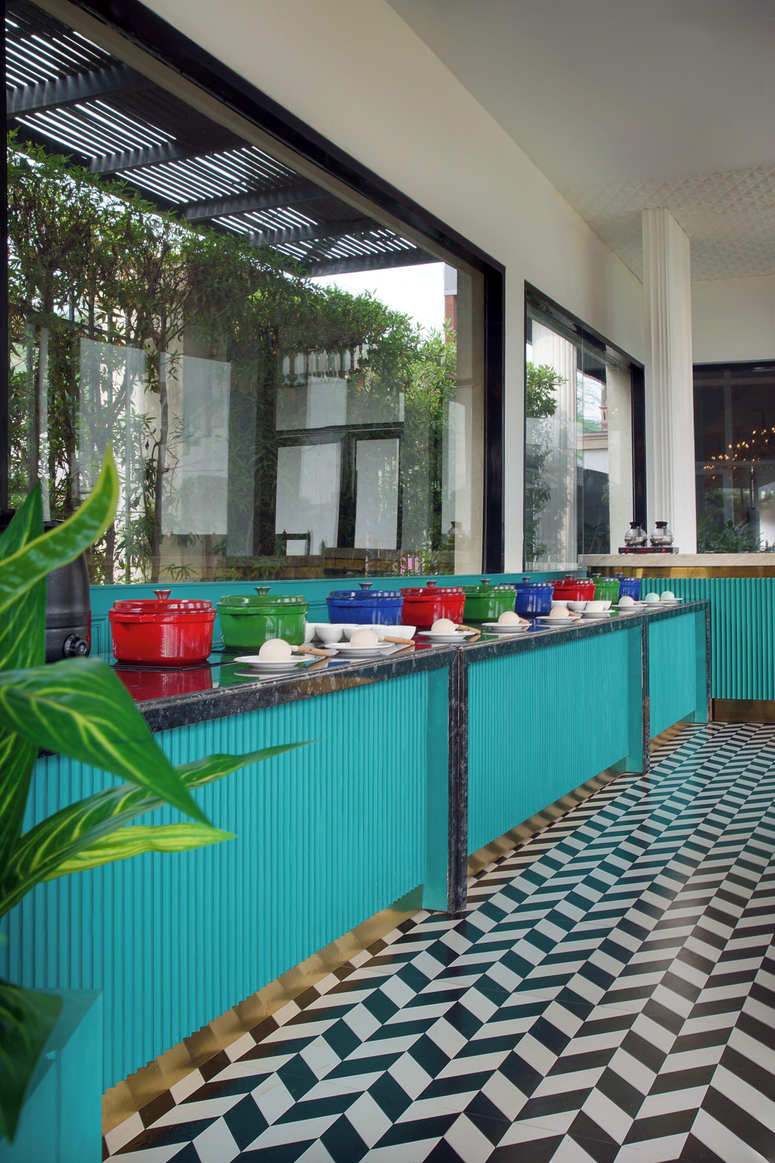 Una cucina con un piano di lavoro verde acqua, ampie finestre e un pavimento decorato.