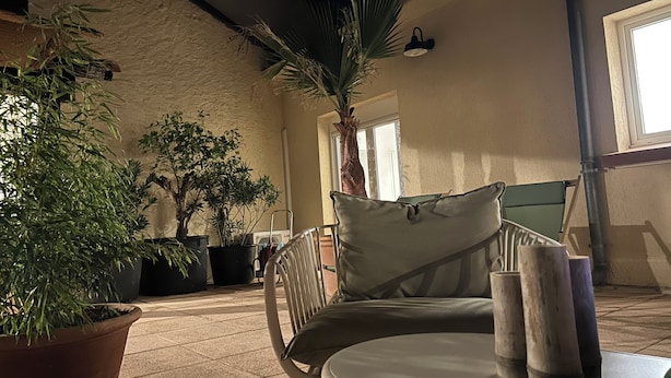 Un espace extérieur aménagé avec une table, des chaises et des plantes en pot.