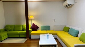 A living room with a green and yellow sofa set, a white coffee table, and a wooden floor. - The whole building can be rented (only for guests) Long term welcome Outlet 7 min walk 11 people 1 bedding per person, no hassle Max 12 people, clean, spacious with Japanese style rooms 4 free parking spaces 4 bedrooms BBQ reservations possible (木更津市)